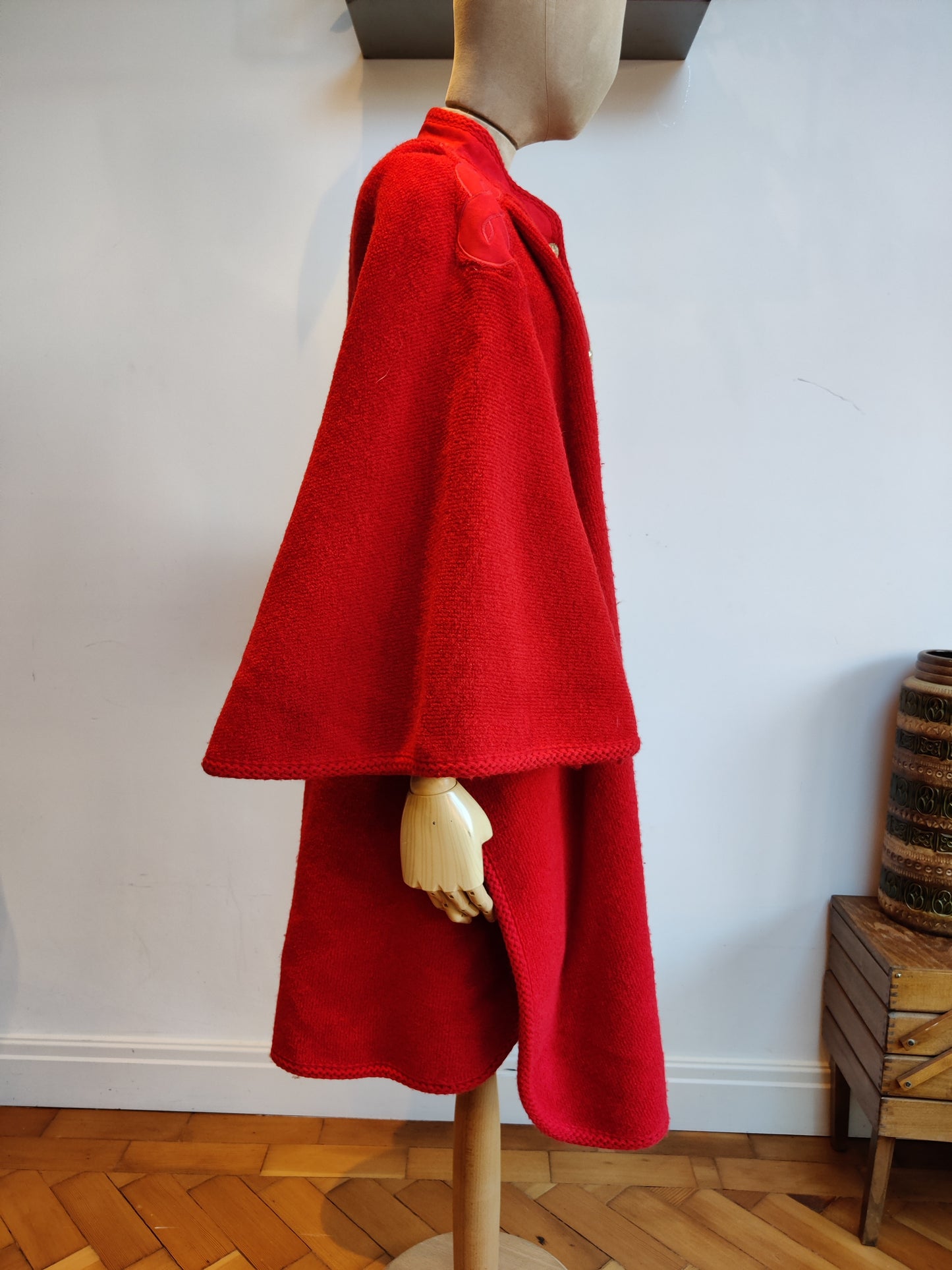 Mid length red cape with statement shoulders.