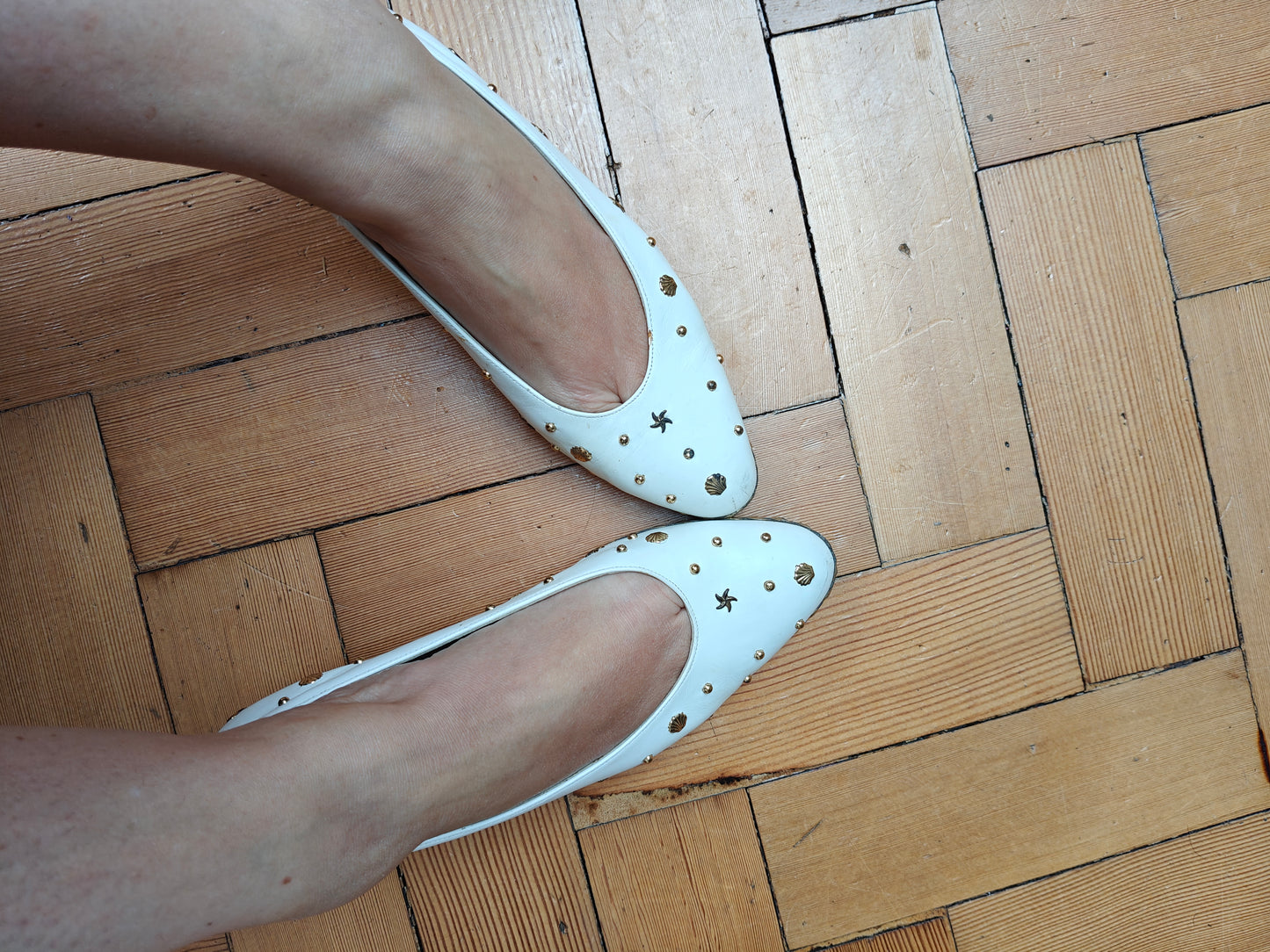 White wedge shoes with star patterns on a wooden floor