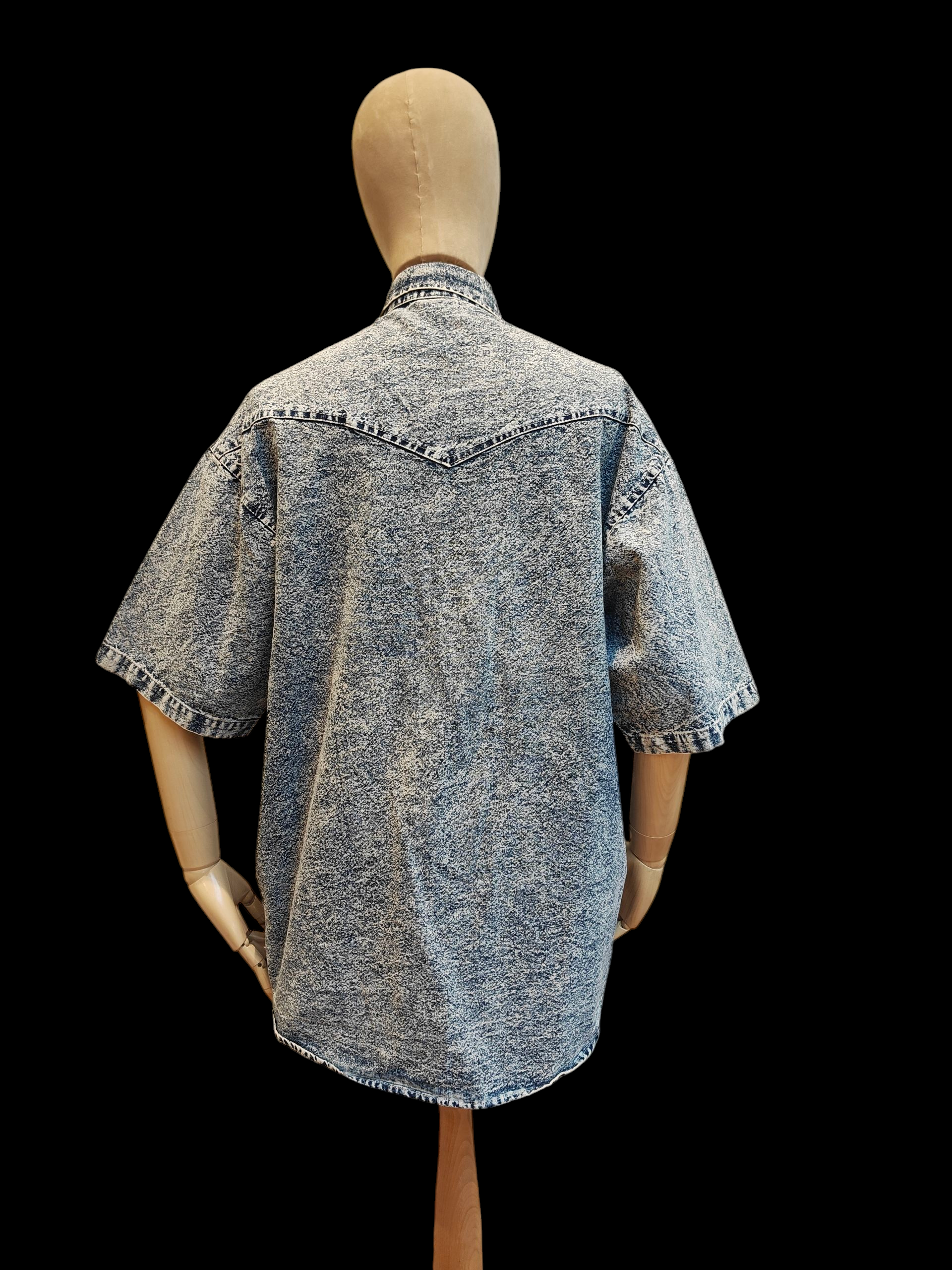 Mannequin wearing a distressed denim shirt on a black background