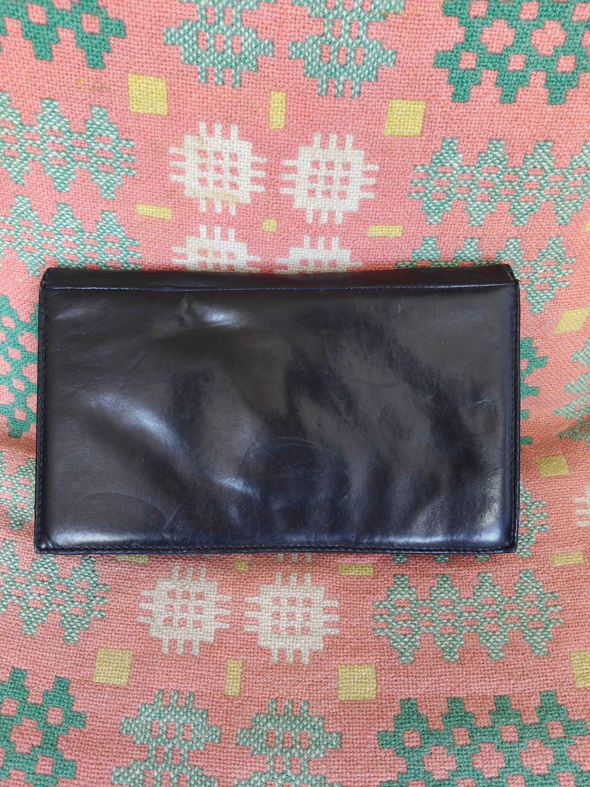 Black leather wallet on a patterned fabric background