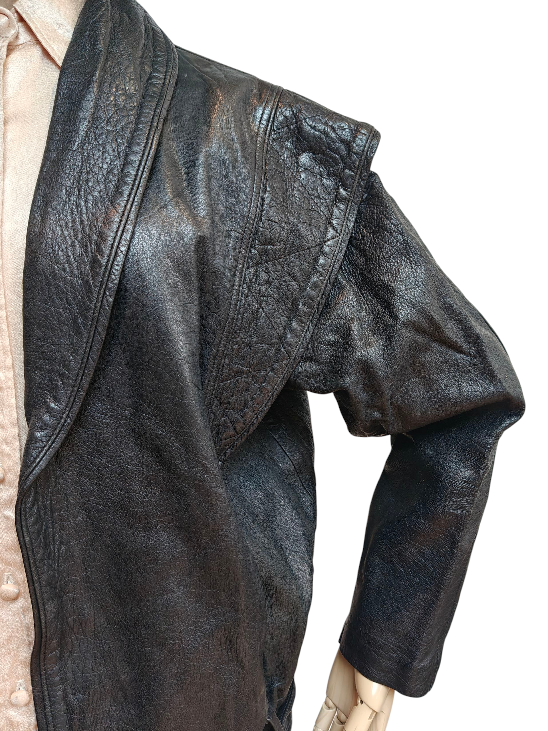 Close-up of a dark leather jacket on a mannequin against a white background