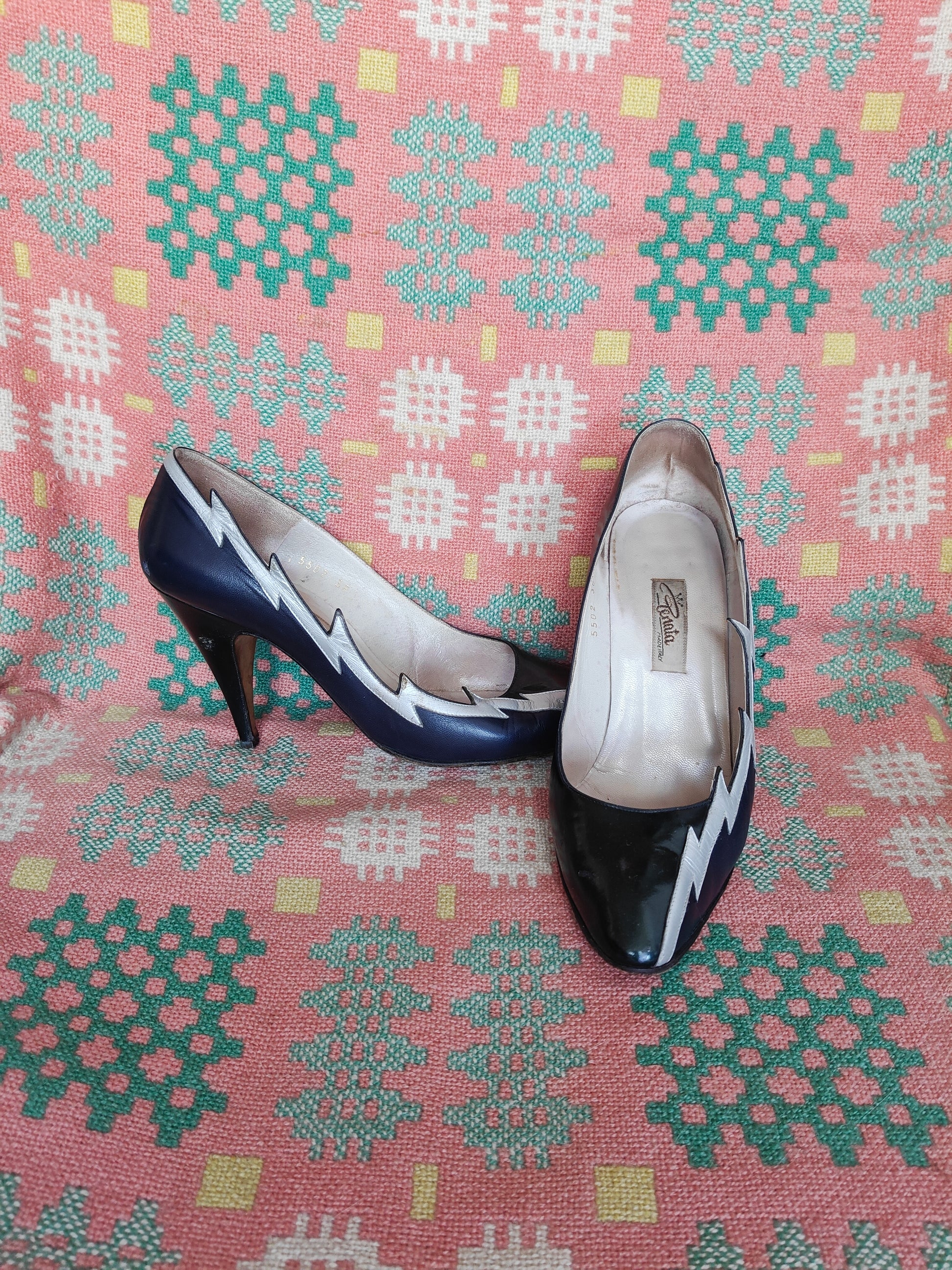 Pair of high-heeled shoes on a patterned fabric background