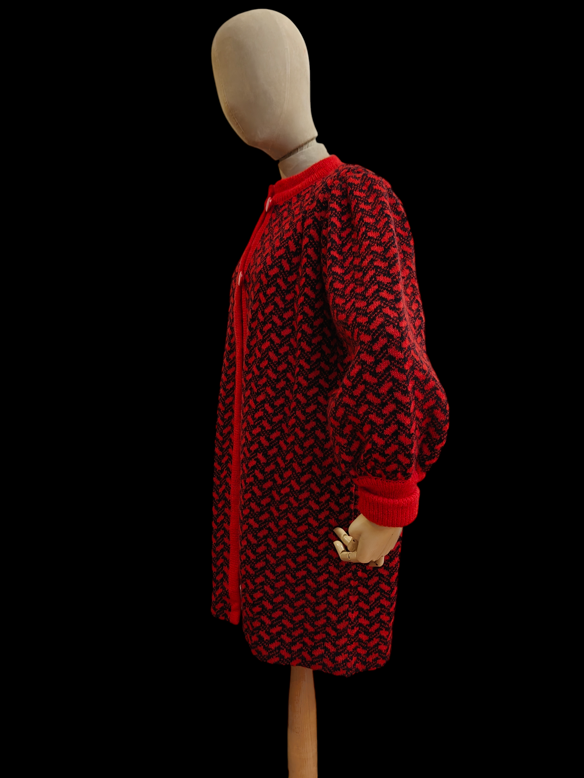 Mannequin wearing a red and black patterned coat on a black background