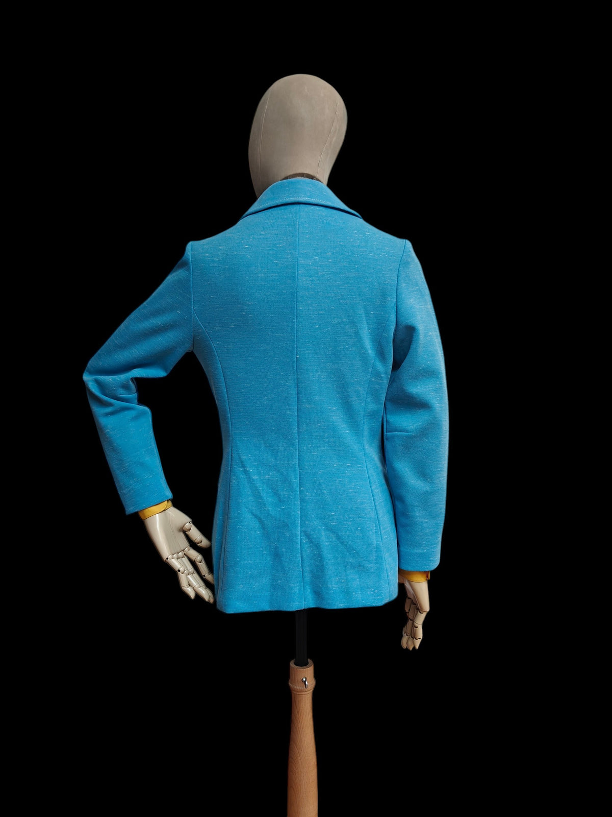 A bright blue vintage tailored blazer shown from the back on a mannequin against a solid black background.
