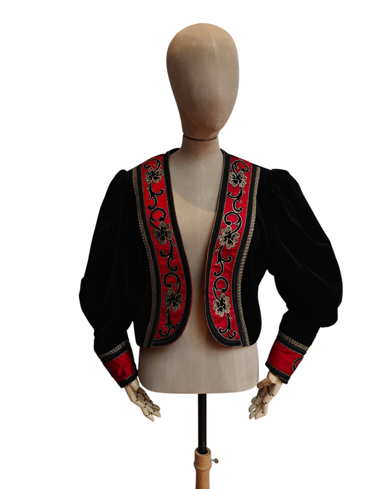 Black embroidered jacket with red and gold details on a mannequin against a white background