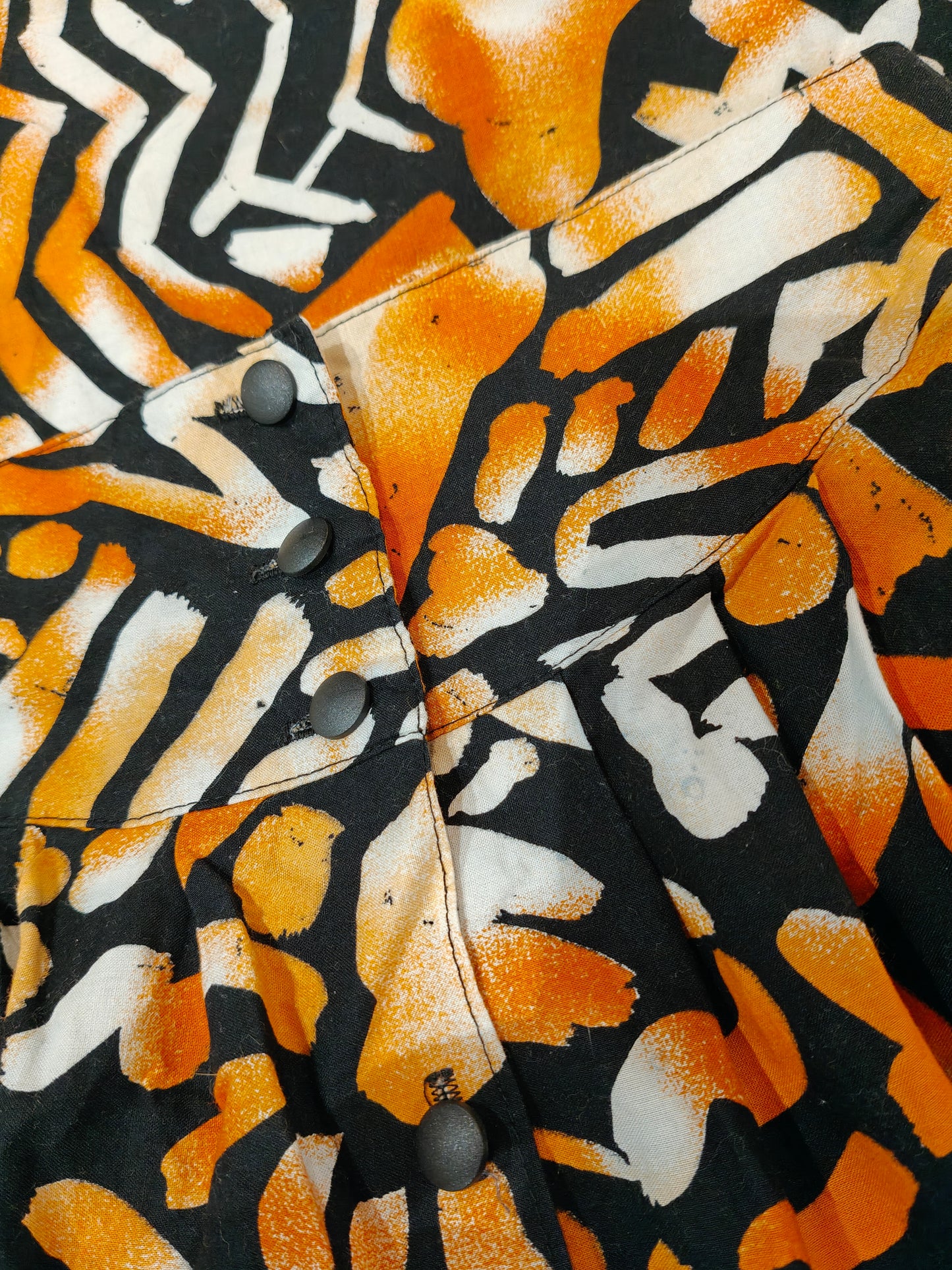 Close-up of a shirt with orange, black, and white abstract pattern