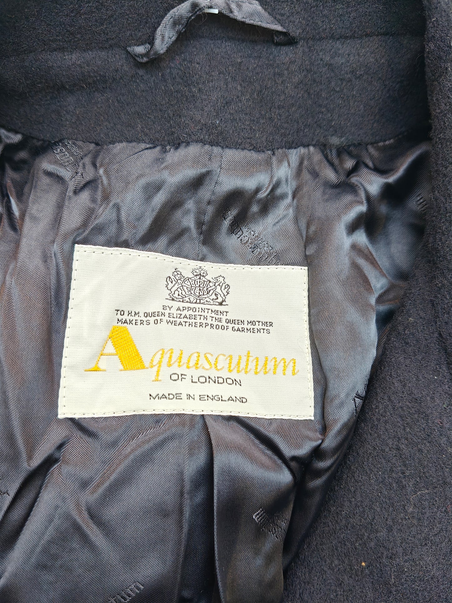 Aquascutum label on a dark fabric background