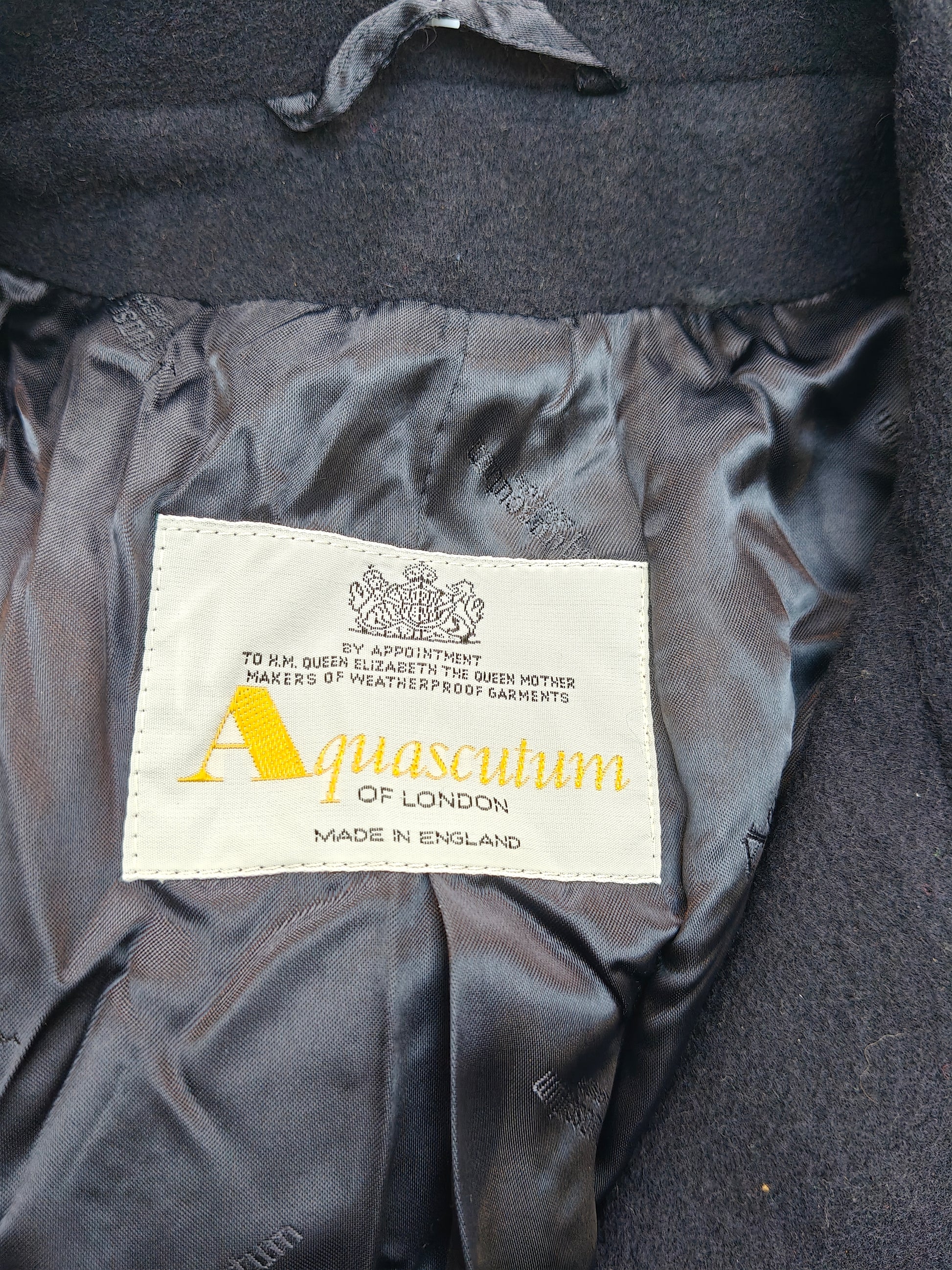 Aquascutum label on a dark fabric background