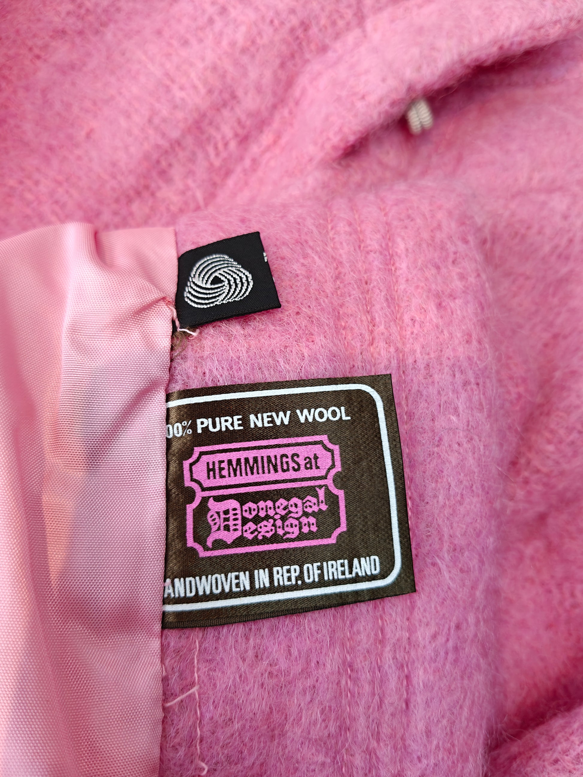 Pink fabric with a label indicating '100% Pure New Wool' and 'Handwoven in Rep. of Ireland'.