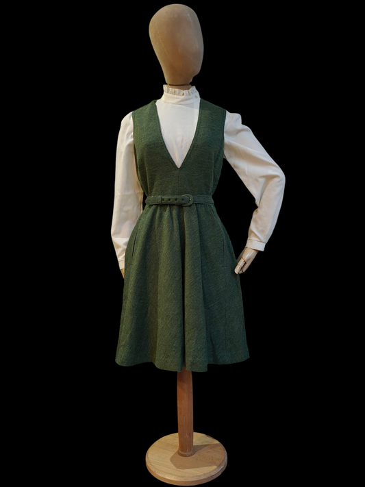 Mannequin wearing a green dress over a white shirt on a black background