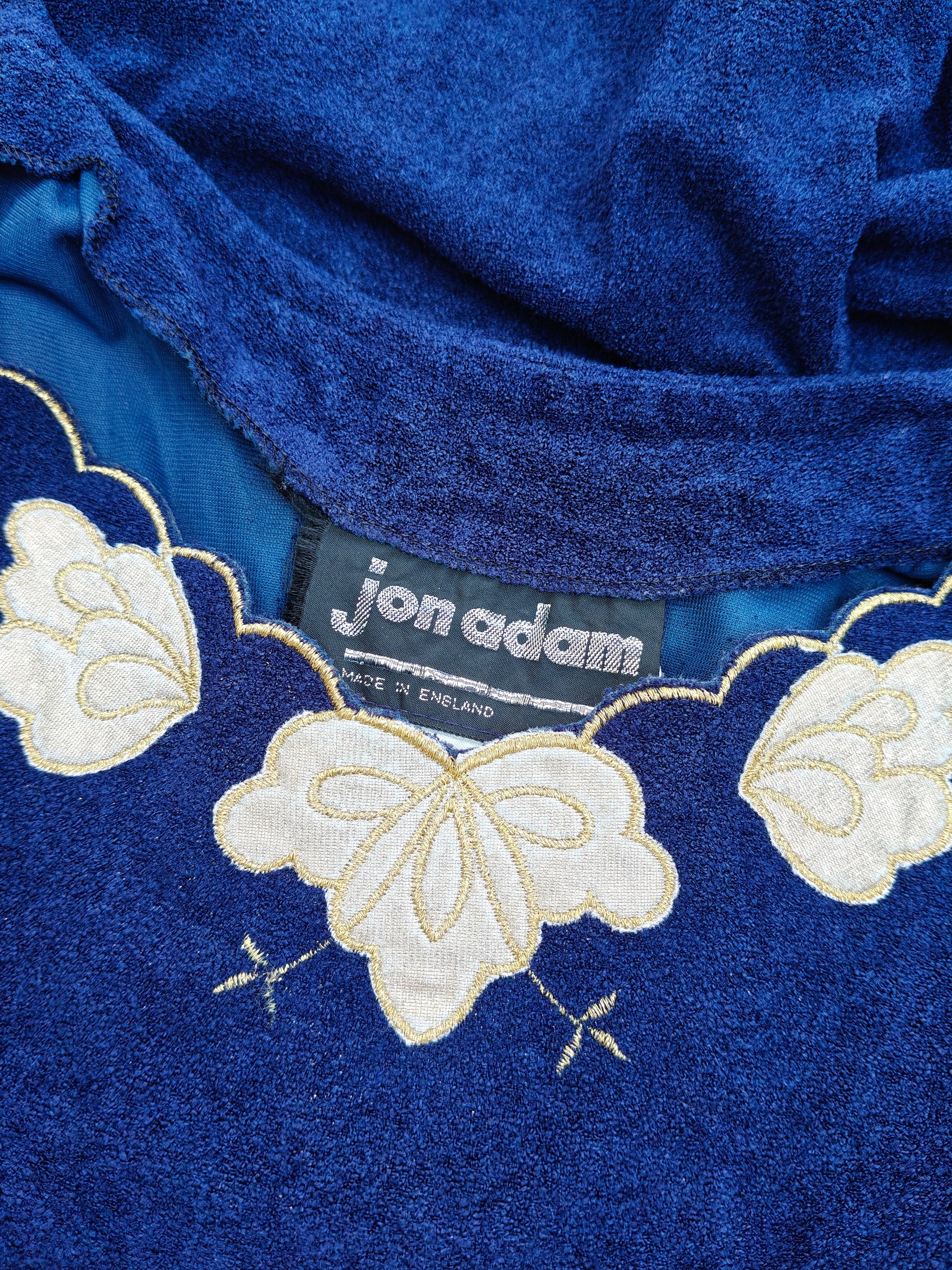 Blue fabric with gold floral embroidery and a visible brand label.
