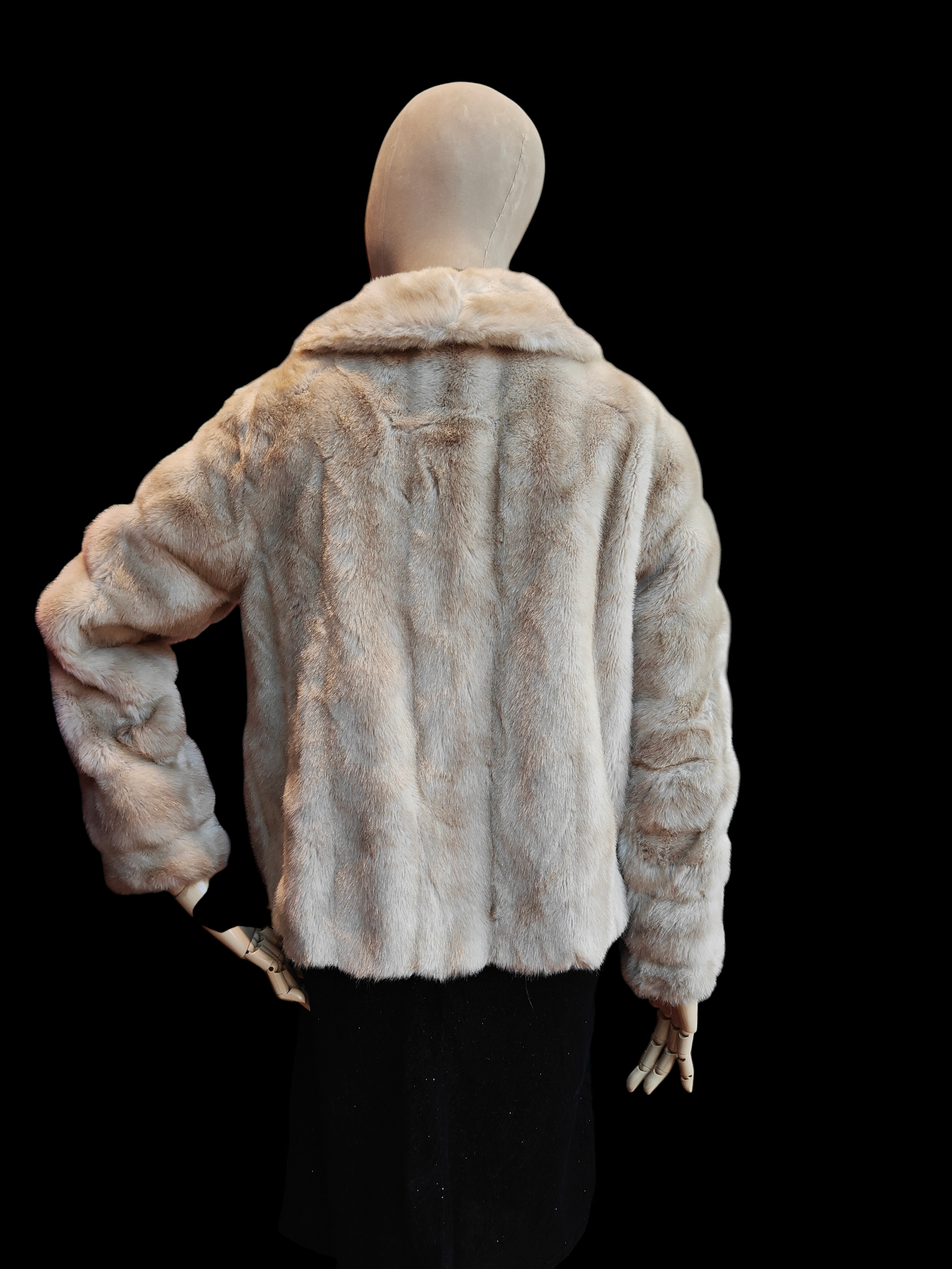 Mannequin wearing a light faux fur coat on a black background