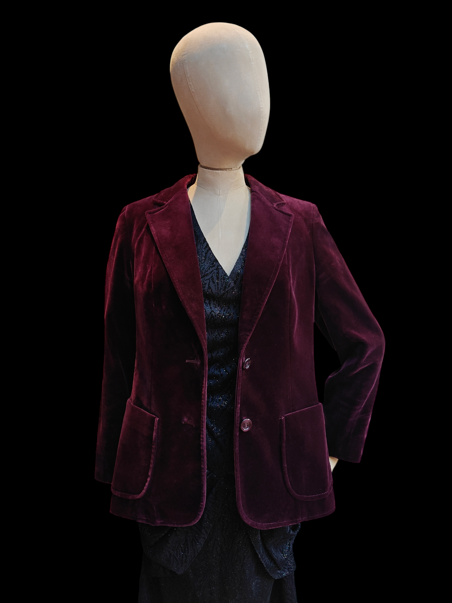 Mannequin wearing a burgundy velvet blazer on a black background