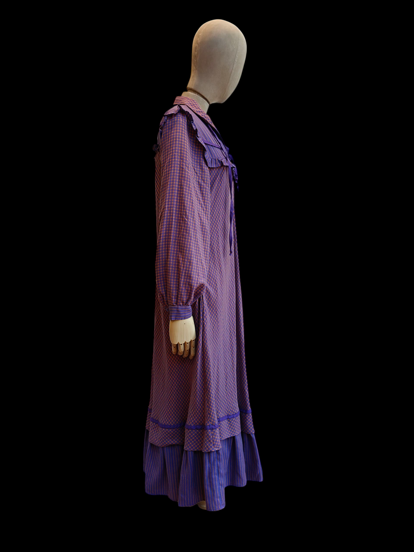 Mannequin wearing a long purple dress with a black background