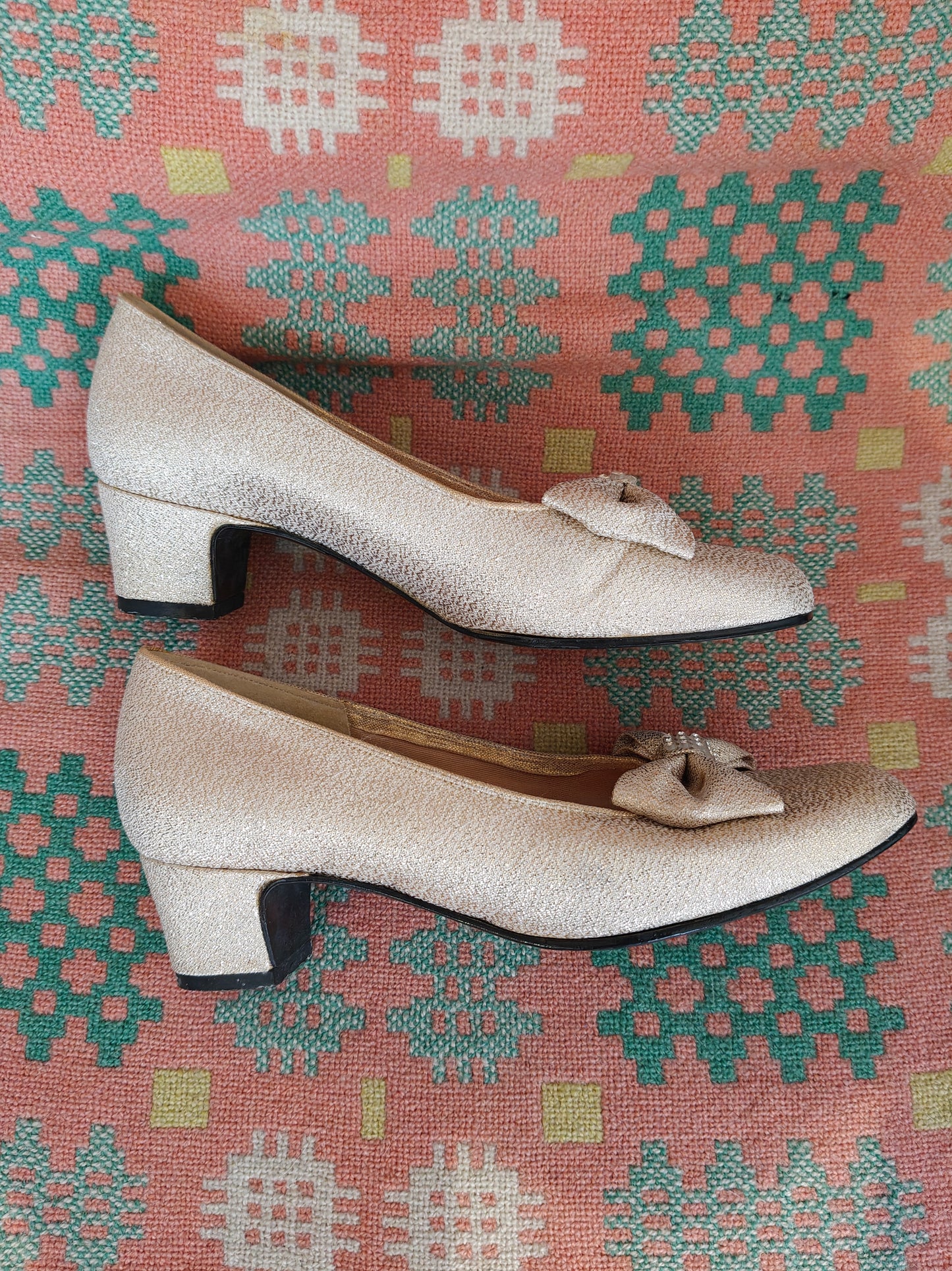 Pair of vintage shoes with a bow on a patterned fabric background