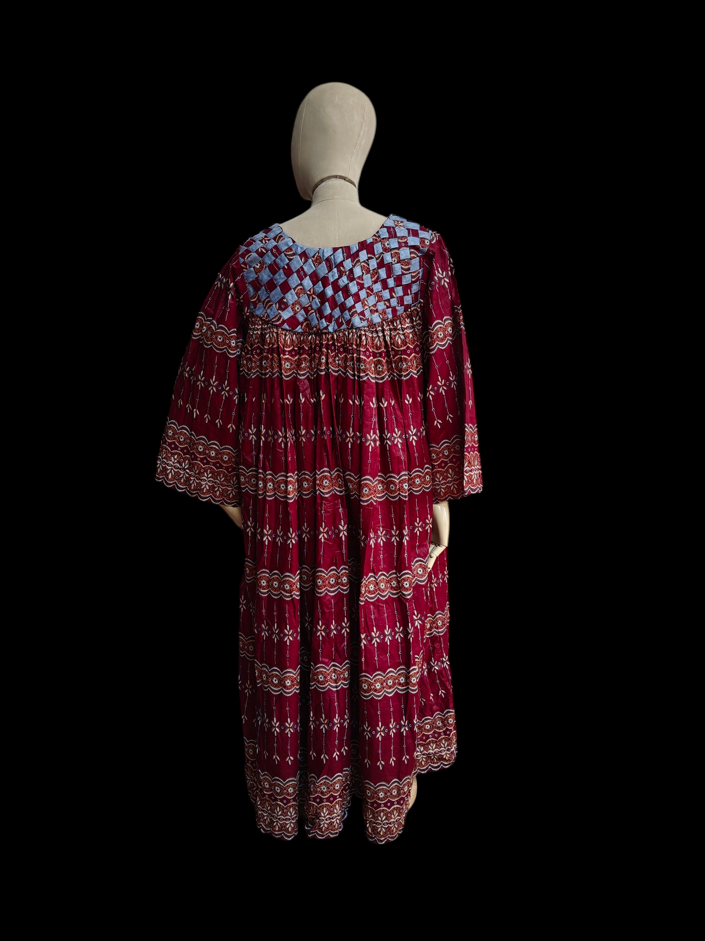 Red patterned dress on a mannequin against a black background