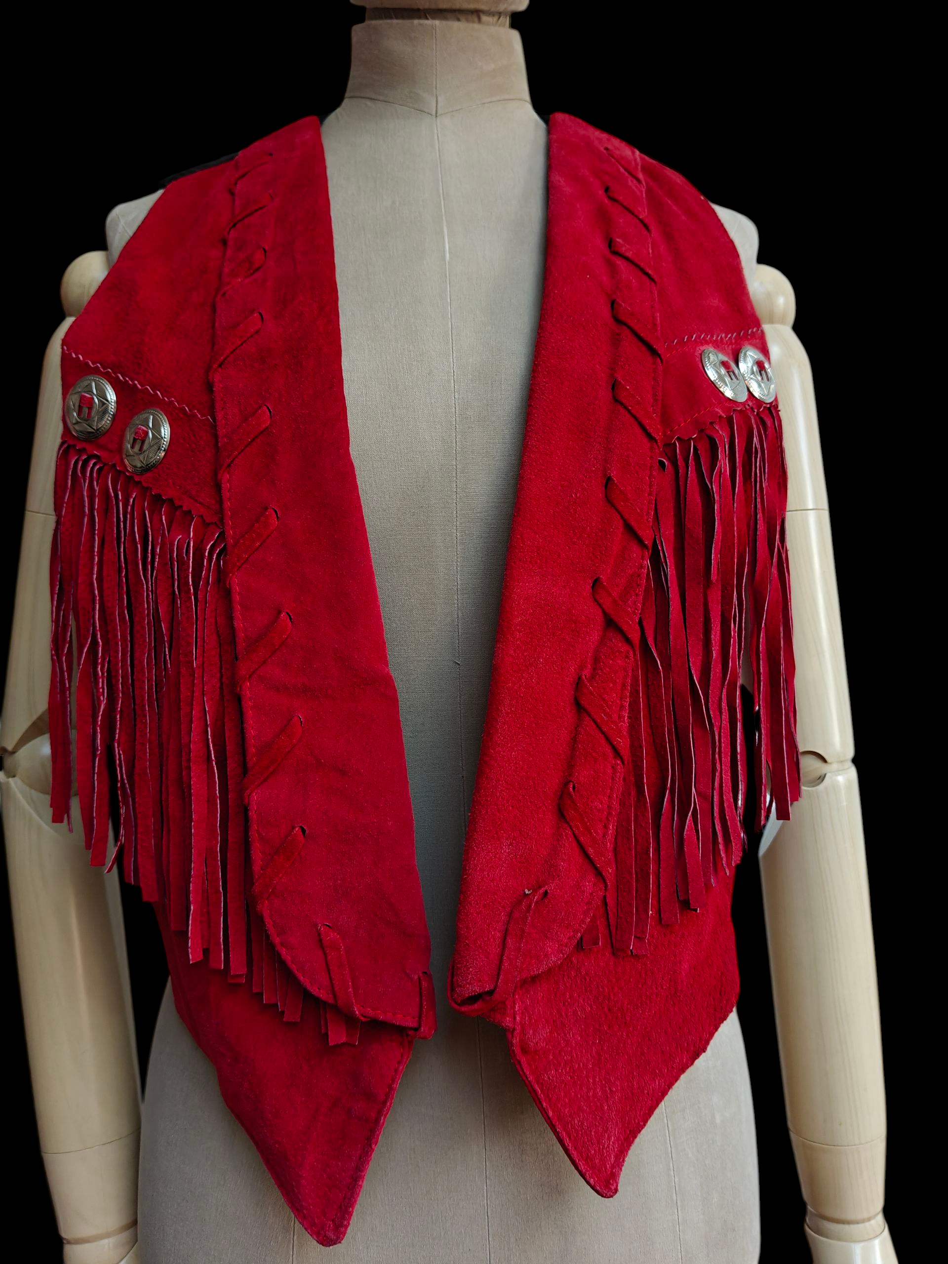 Red fringed vest on a mannequin against a black background