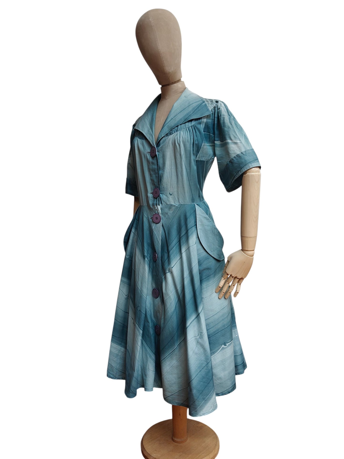 Mannequin wearing a blue patterned 50's dress on a white background