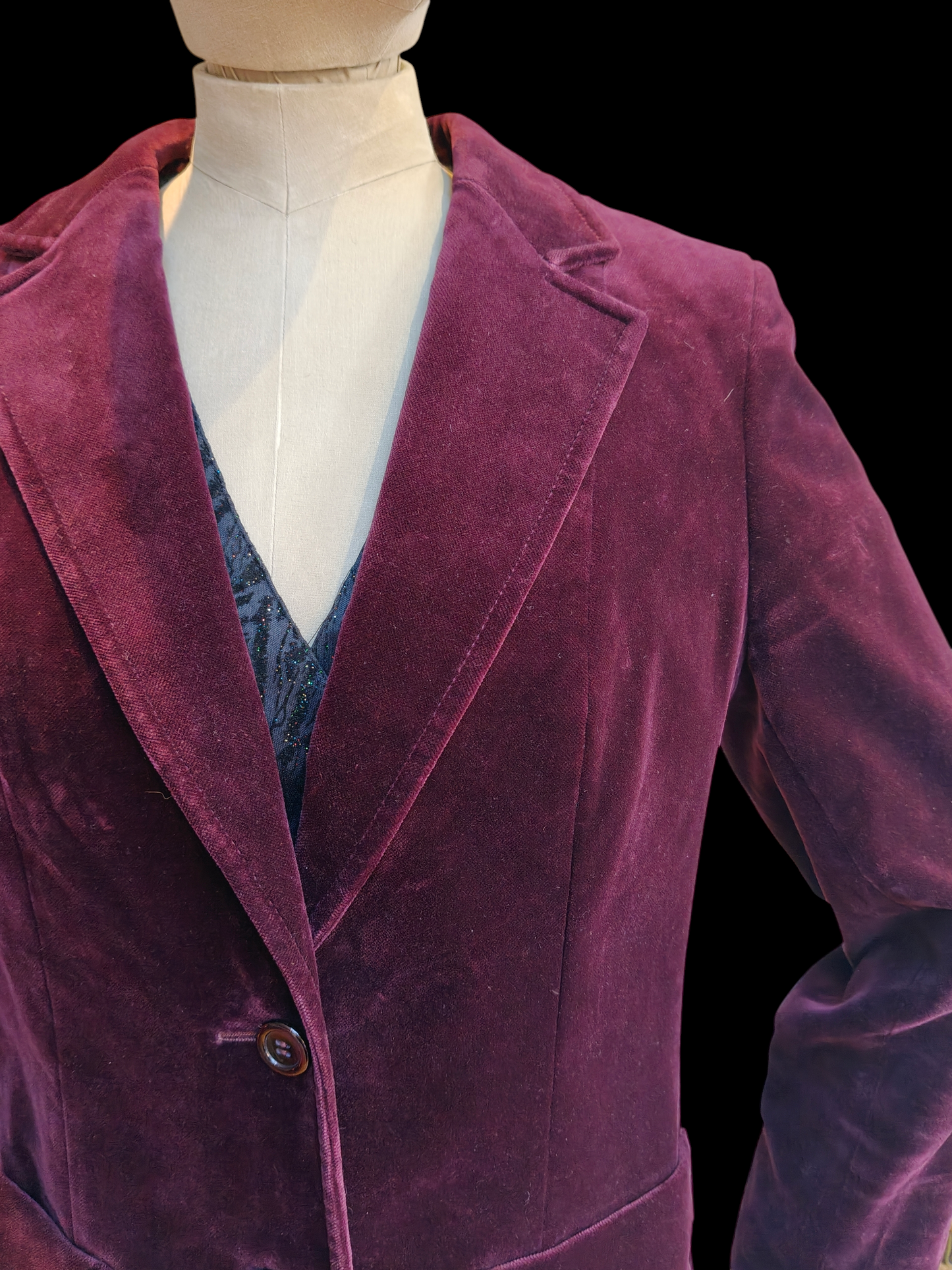 Purple velvet blazer on a mannequin against a black background