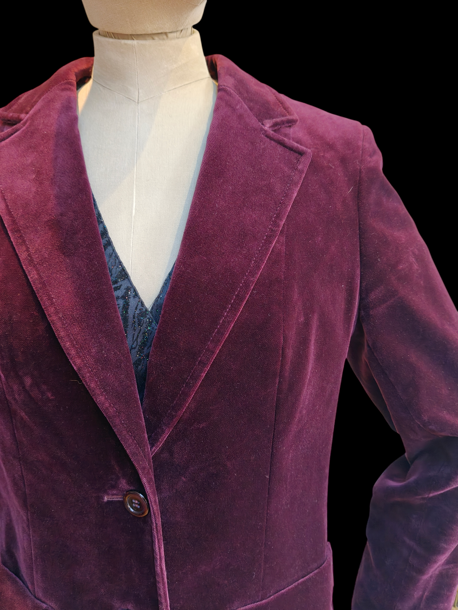 Purple velvet blazer on a mannequin against a black background