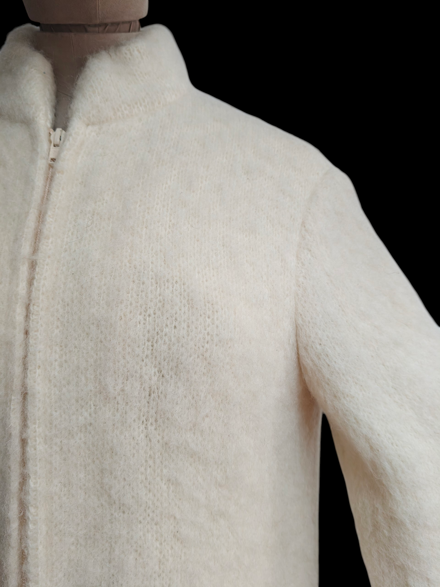 Close-up of a white textured coat on a mannequin against a black background