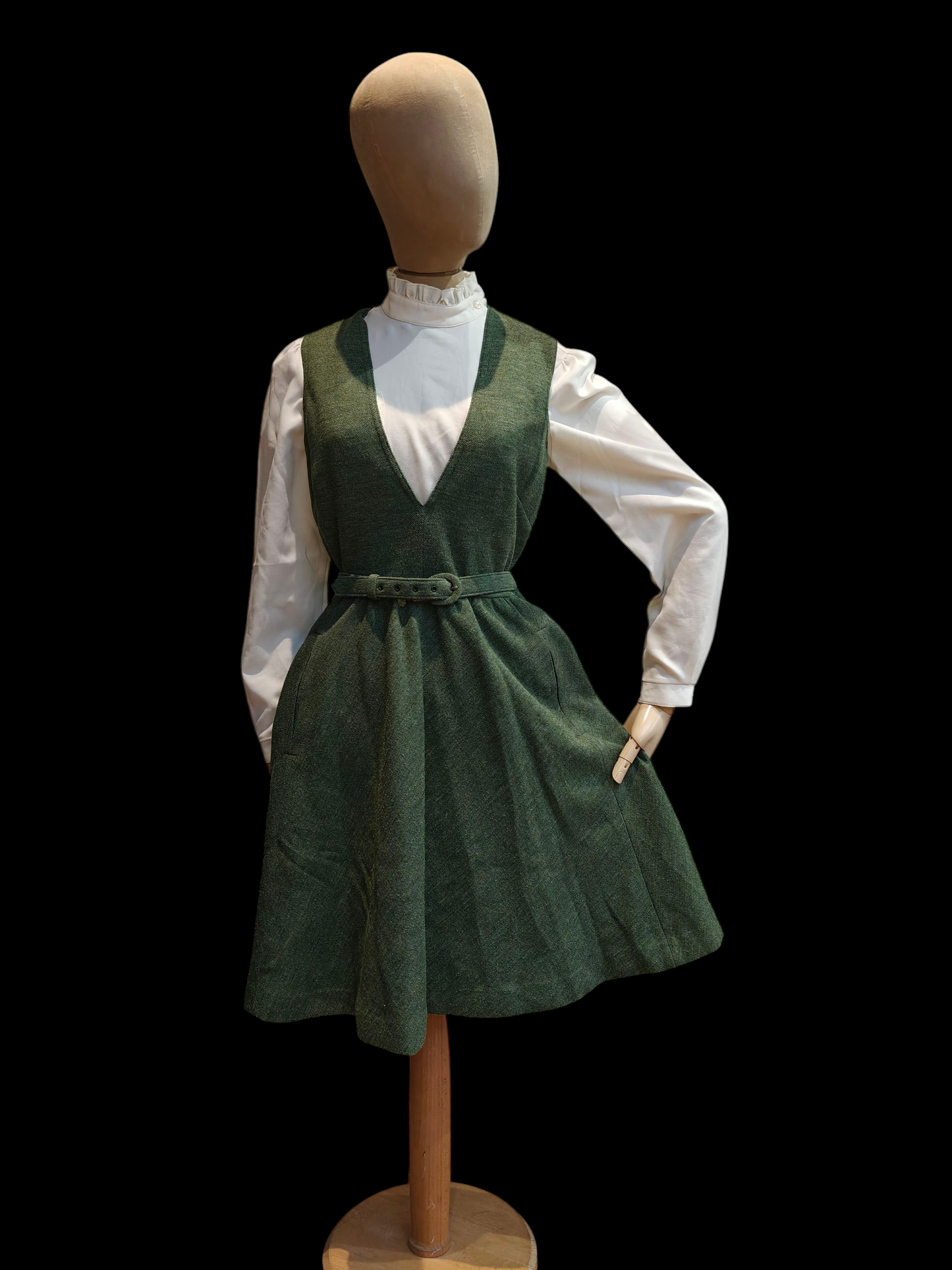 Mannequin wearing a green dress over a white shirt on a black background