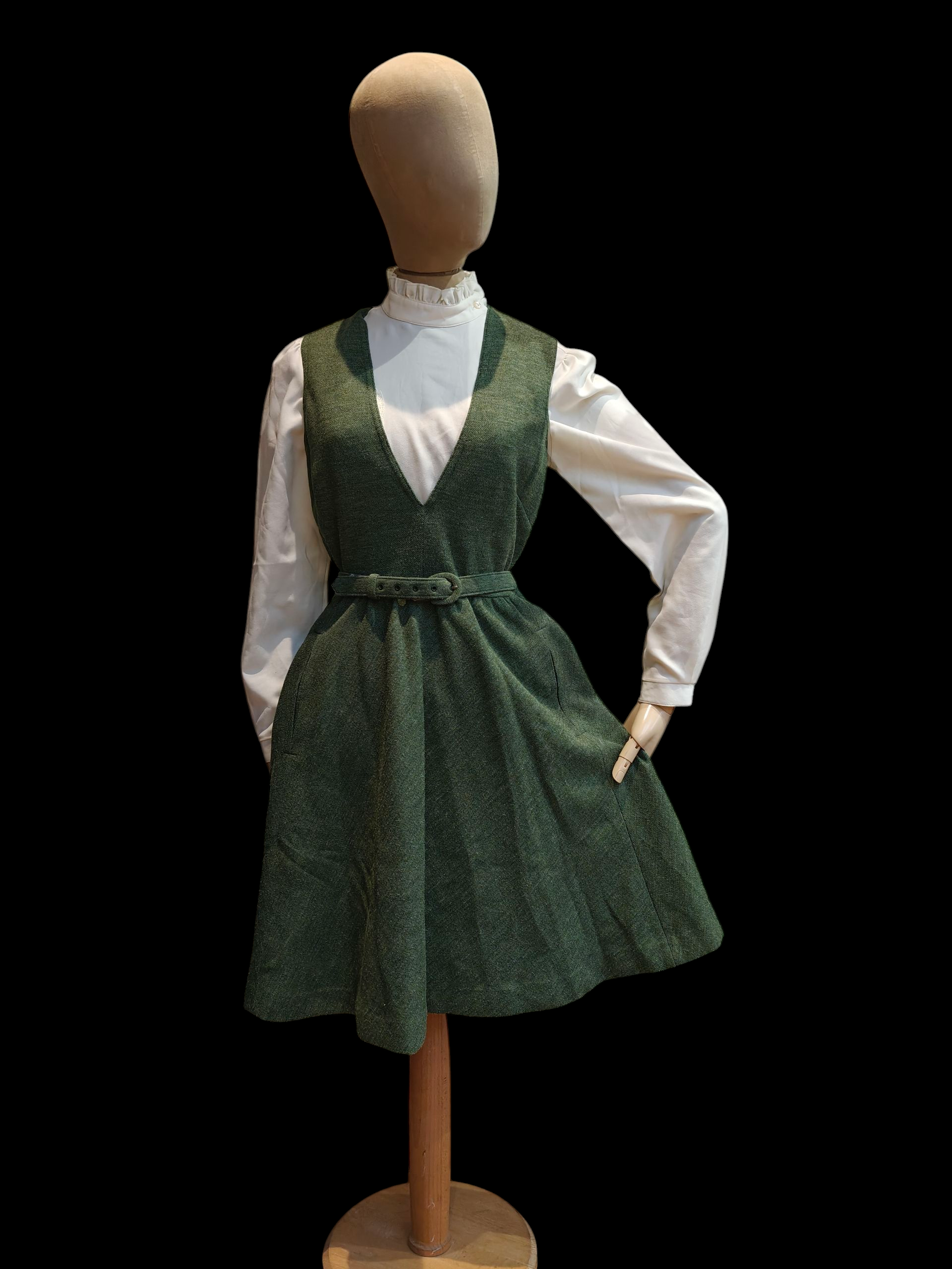 Mannequin wearing a green dress over a white shirt on a black background