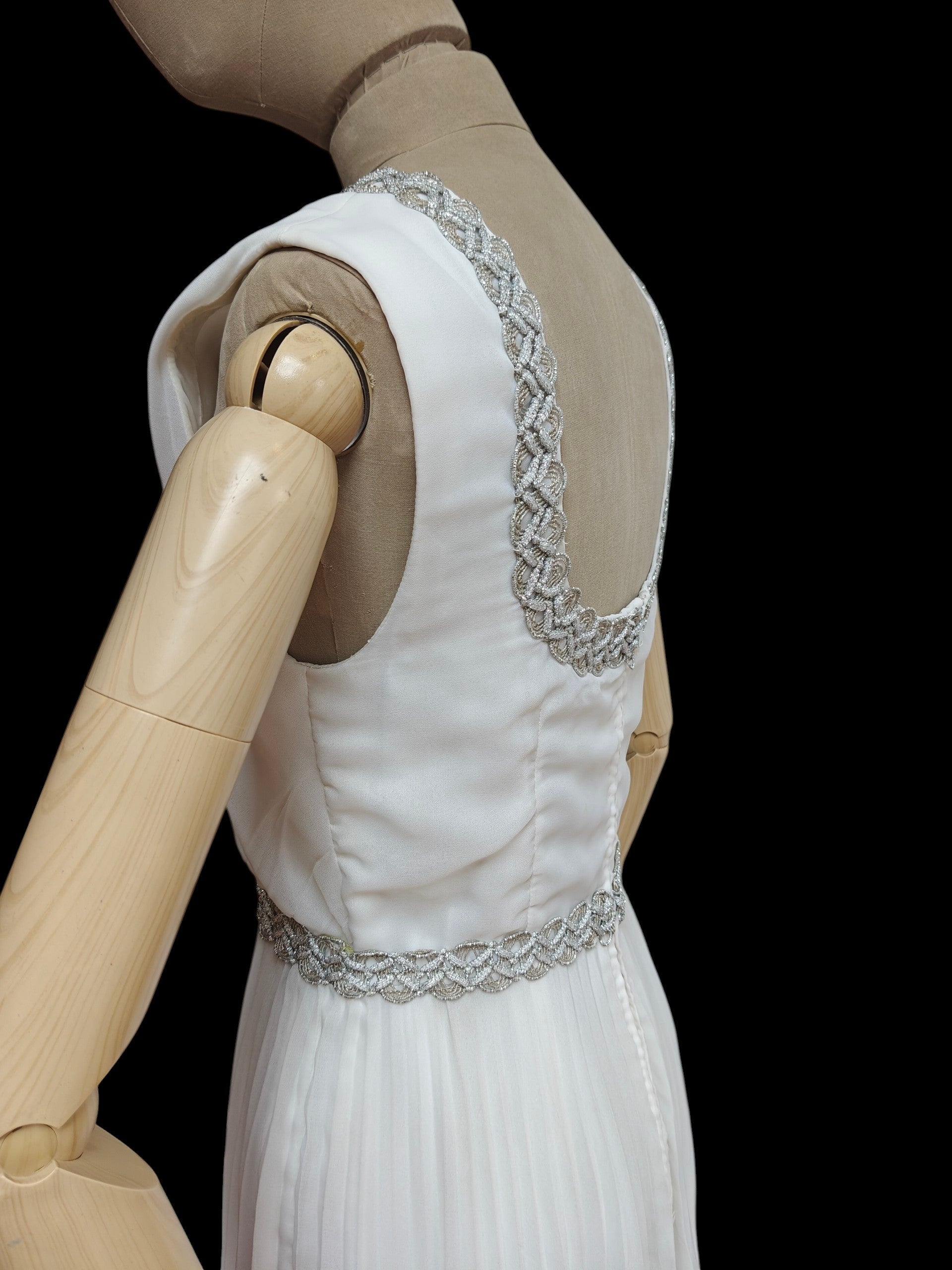 White wedding dress with silver embellishments on a mannequin against a black background