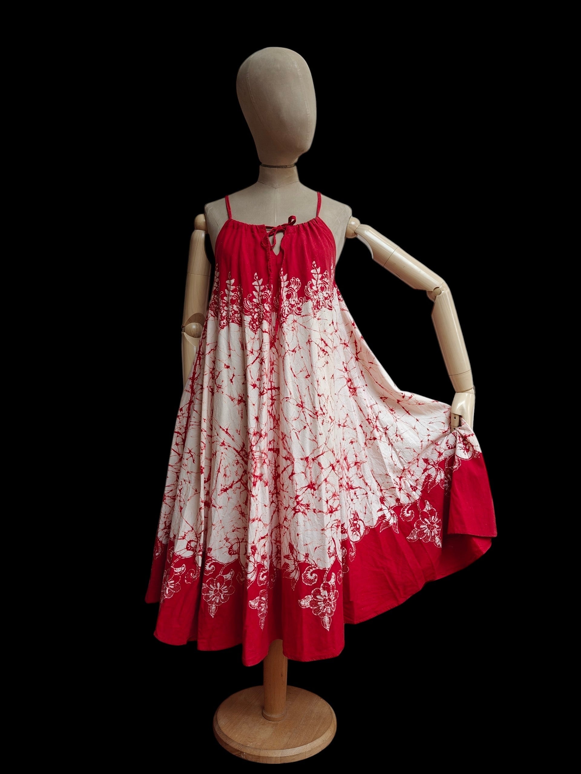 Red and white floral dress on a mannequin against a black background