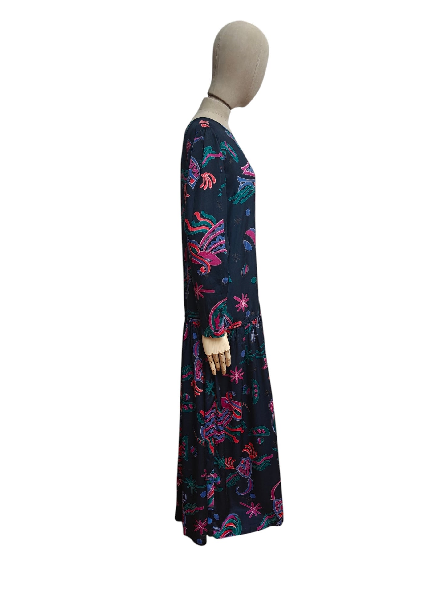 A long-sleeve maxi dress with a vibrant multicolor abstract pattern on a dark navy base, displayed on a mannequin against a plain white background.
