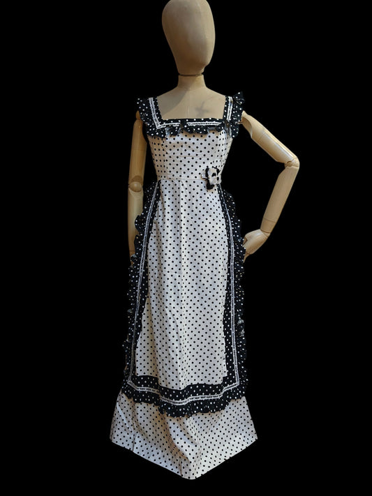 Mannequin wearing a black and white polka dot dress with decorative trim on a black background