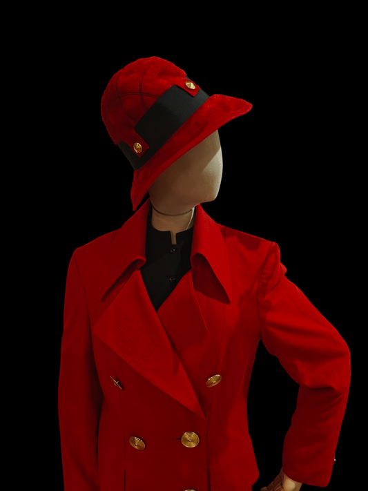 Mannequin wearing a red coat and hat with gold buttons on a black background