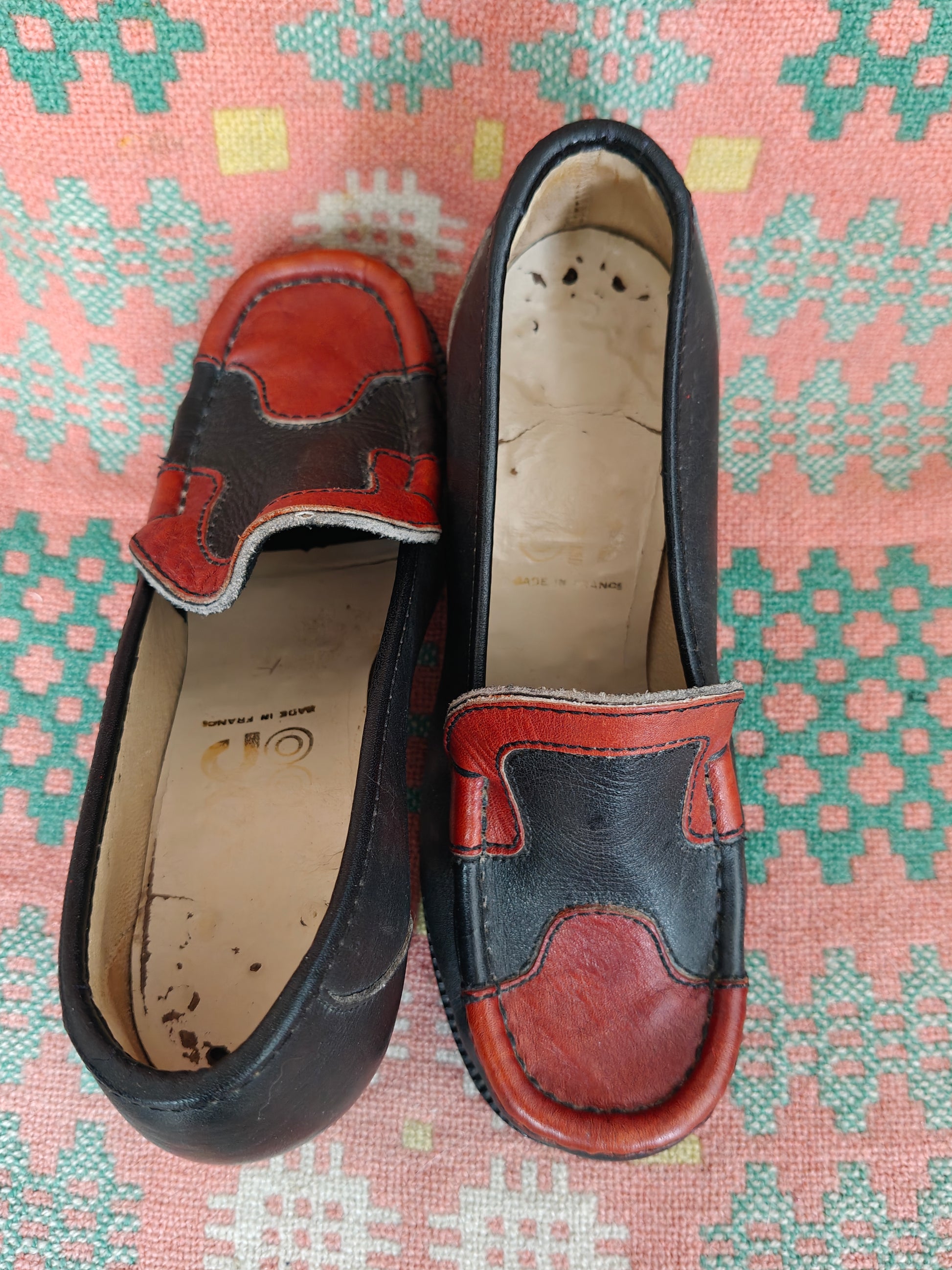 Pair of black and red loafers on a patterned surface