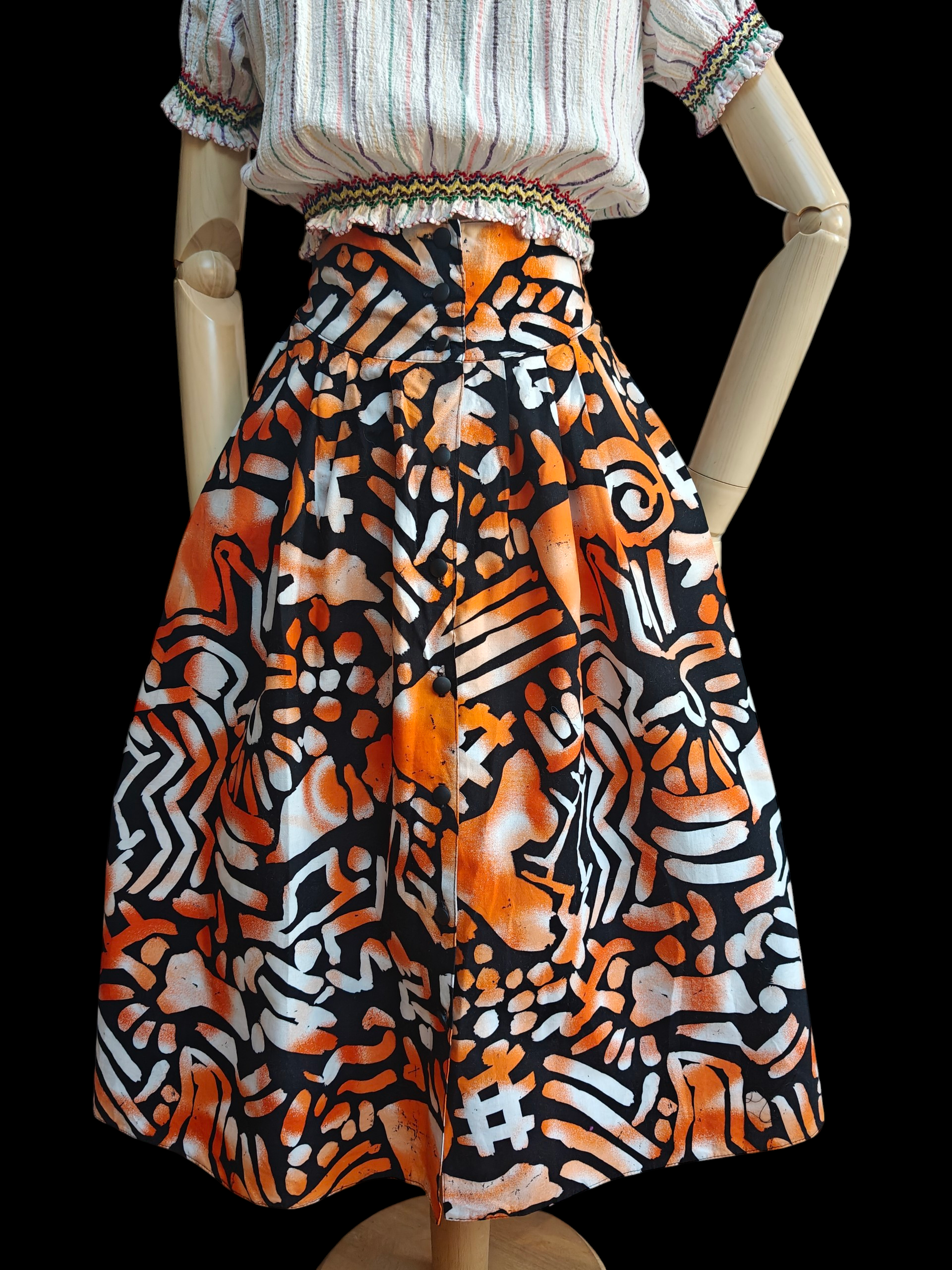 Mannequin wearing a colorful patterned skirt with a plain background