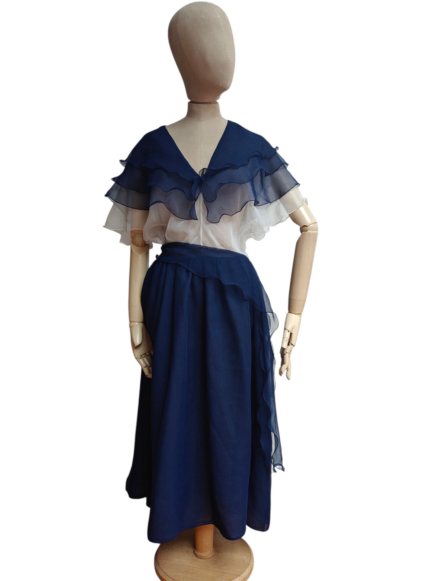 Mannequin wearing a navy blue and white dress with a sheer overlay on a white background